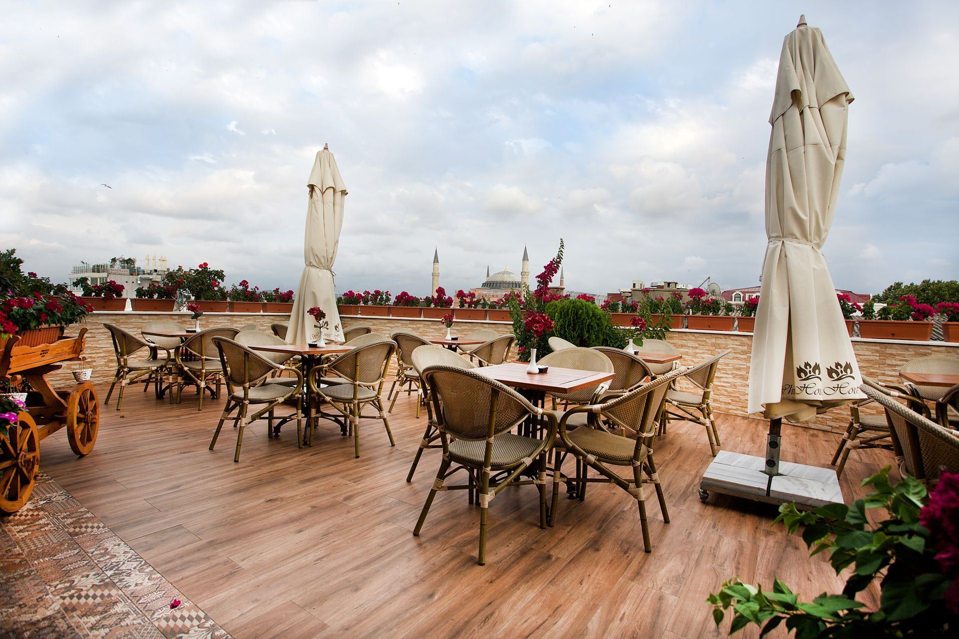 Istanbul white house hotel | Outdoor café terrace with wicker tables and chairs, closed white umbrellas