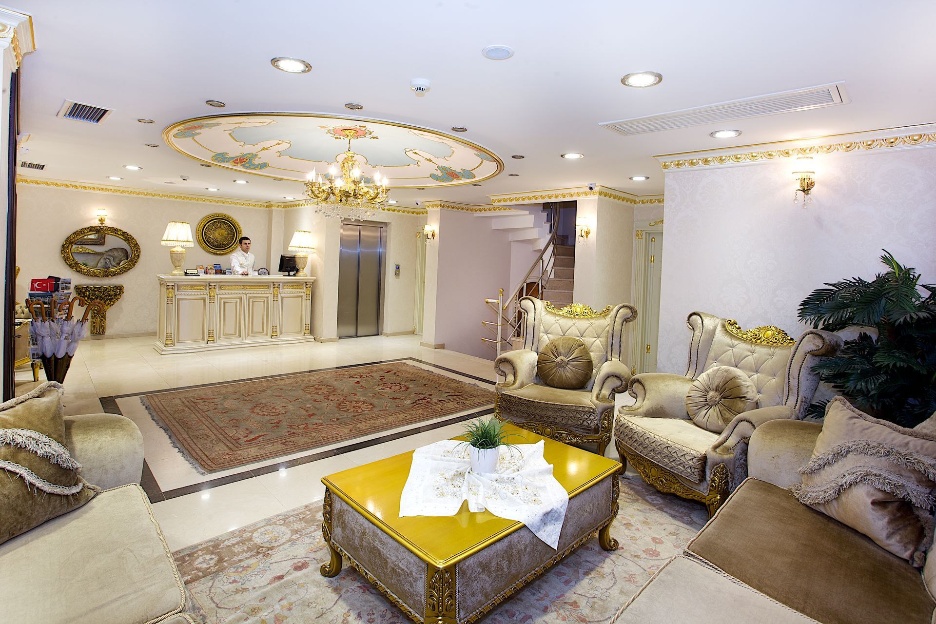 White house Hotel Lobby, Elegant beige living room with ornate gold decor, chandelier, plush sofas, and a coffee table.
