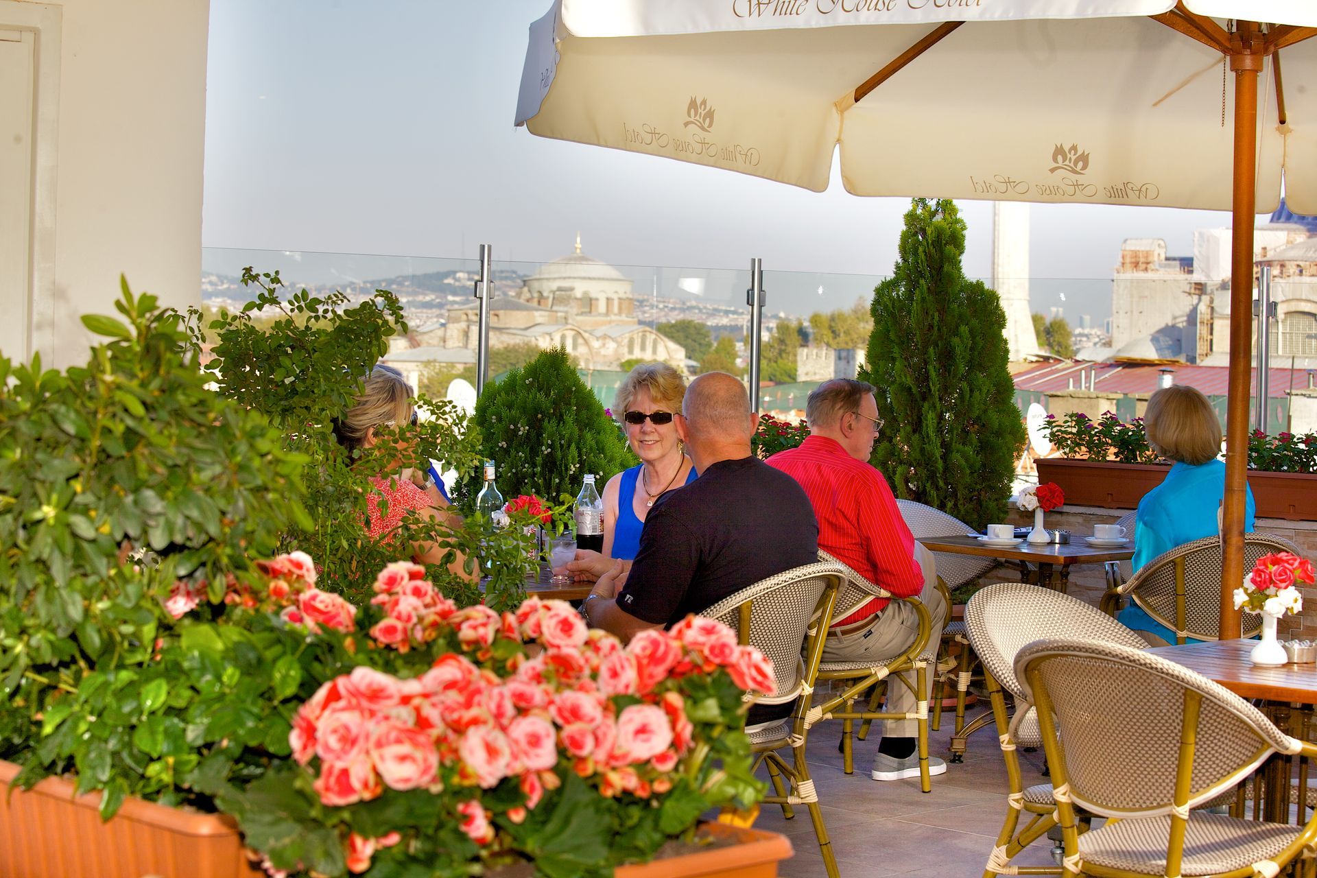 Istanbul white house hotel | People sitting at a café terrace with pink flowers and city skyline in the background