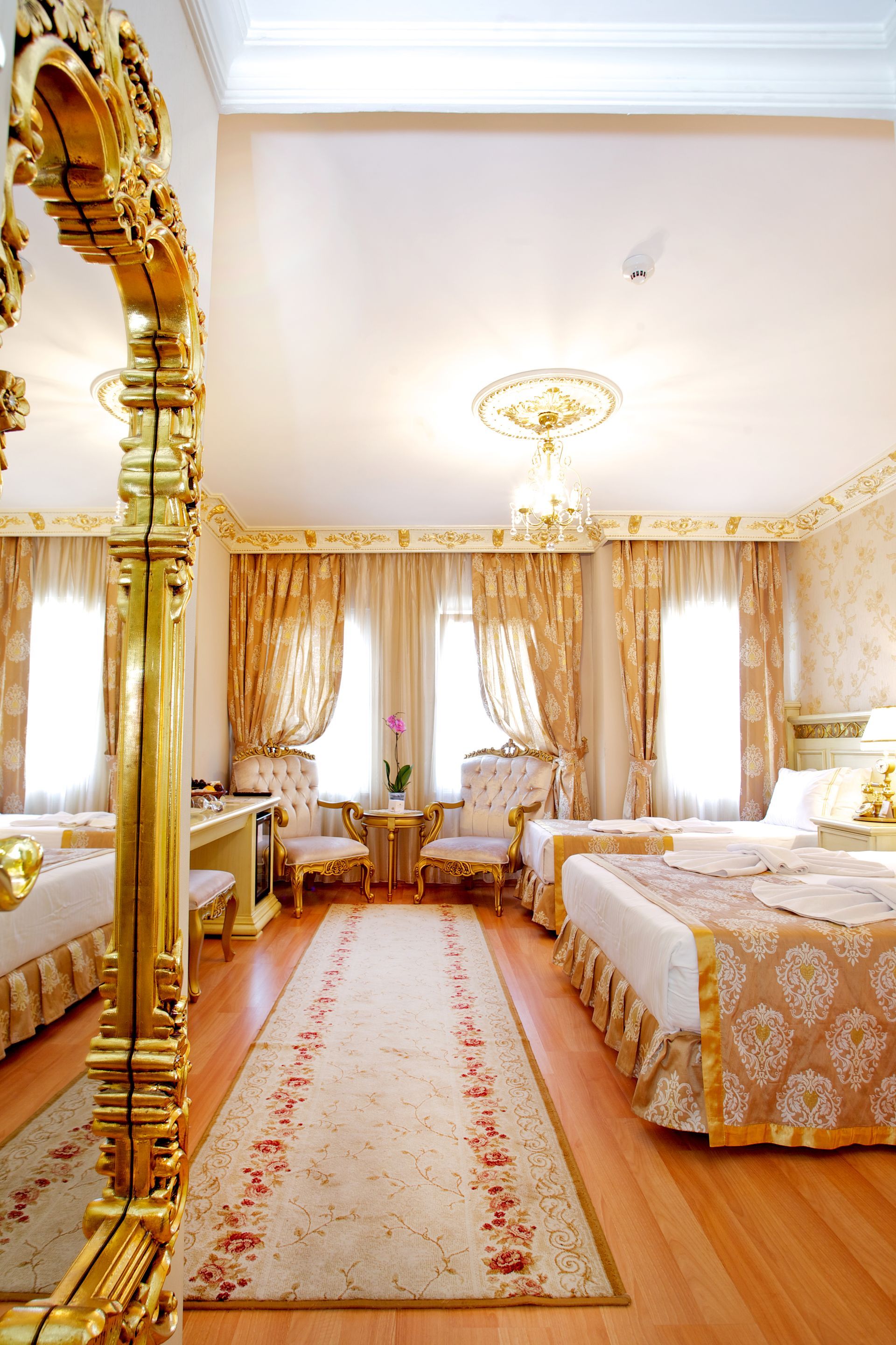 Istanbul white house hotel | Elegant bedroom with gold accents, twin beds, curtains, chandelier, and patterned rug