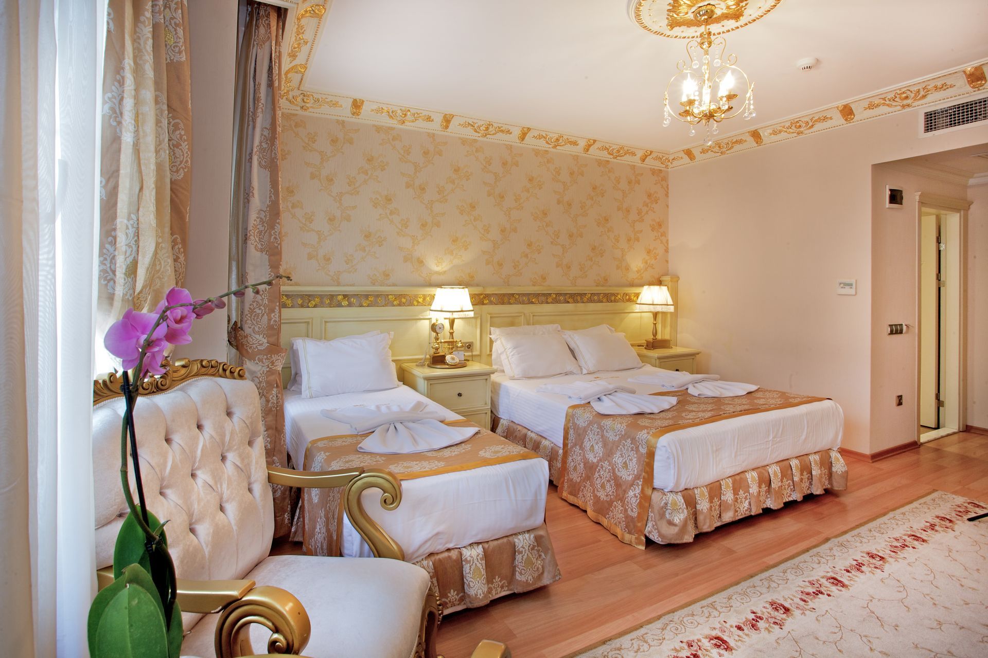Istanbul white house hotel | Elegant hotel room with two twin beds, gold decor, chandelier, and orchid plant