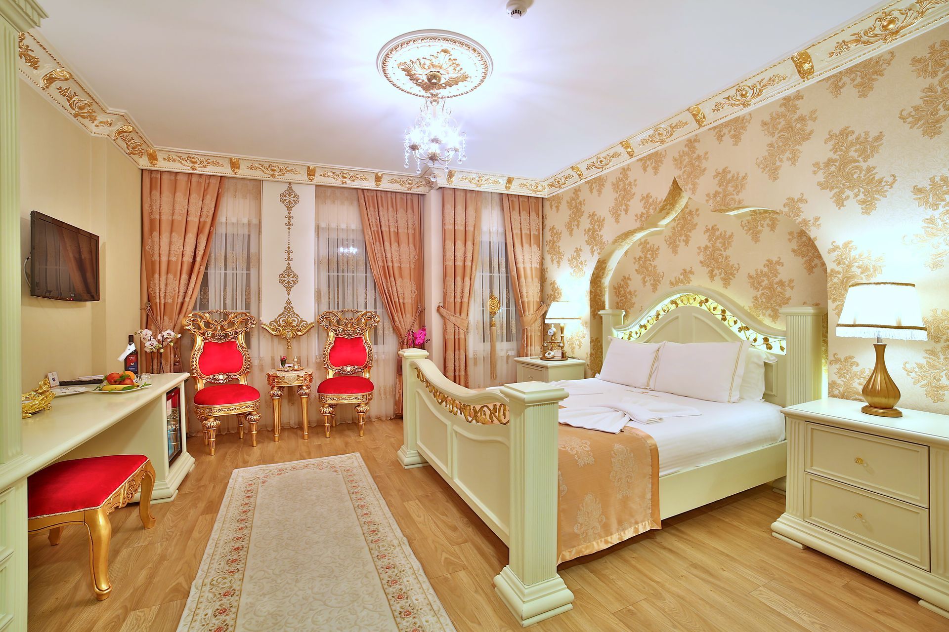 Istanbul white house hotel | Elegant bedroom with ornate gold decor, a white bed, red chairs, and pink curtains