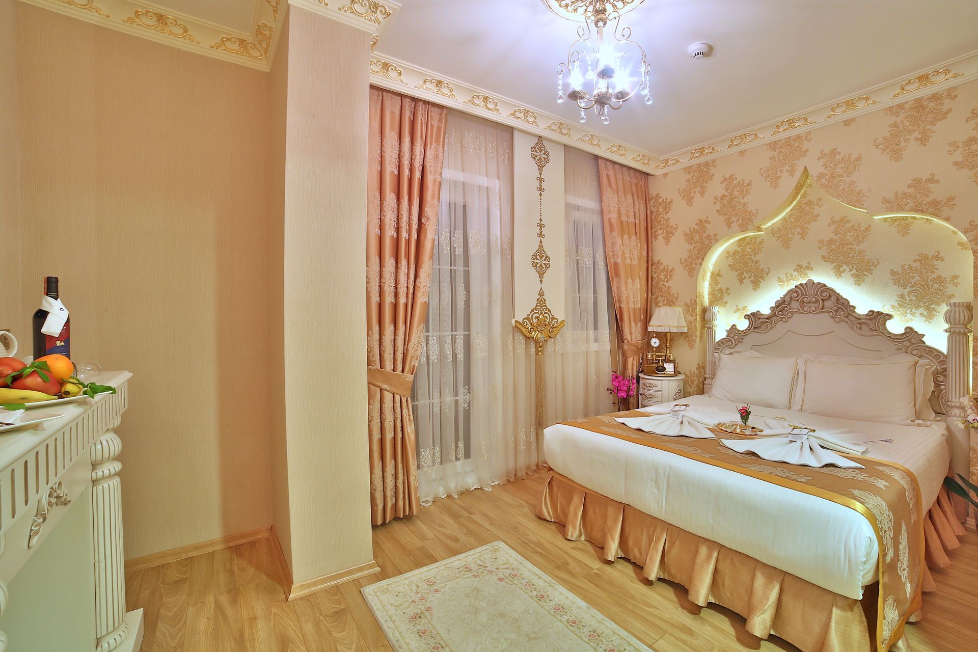 Istanbul white house hotel | Elegant bedroom with a carved canopy bed, pink drapes, chandelier, and ornate cream decor
