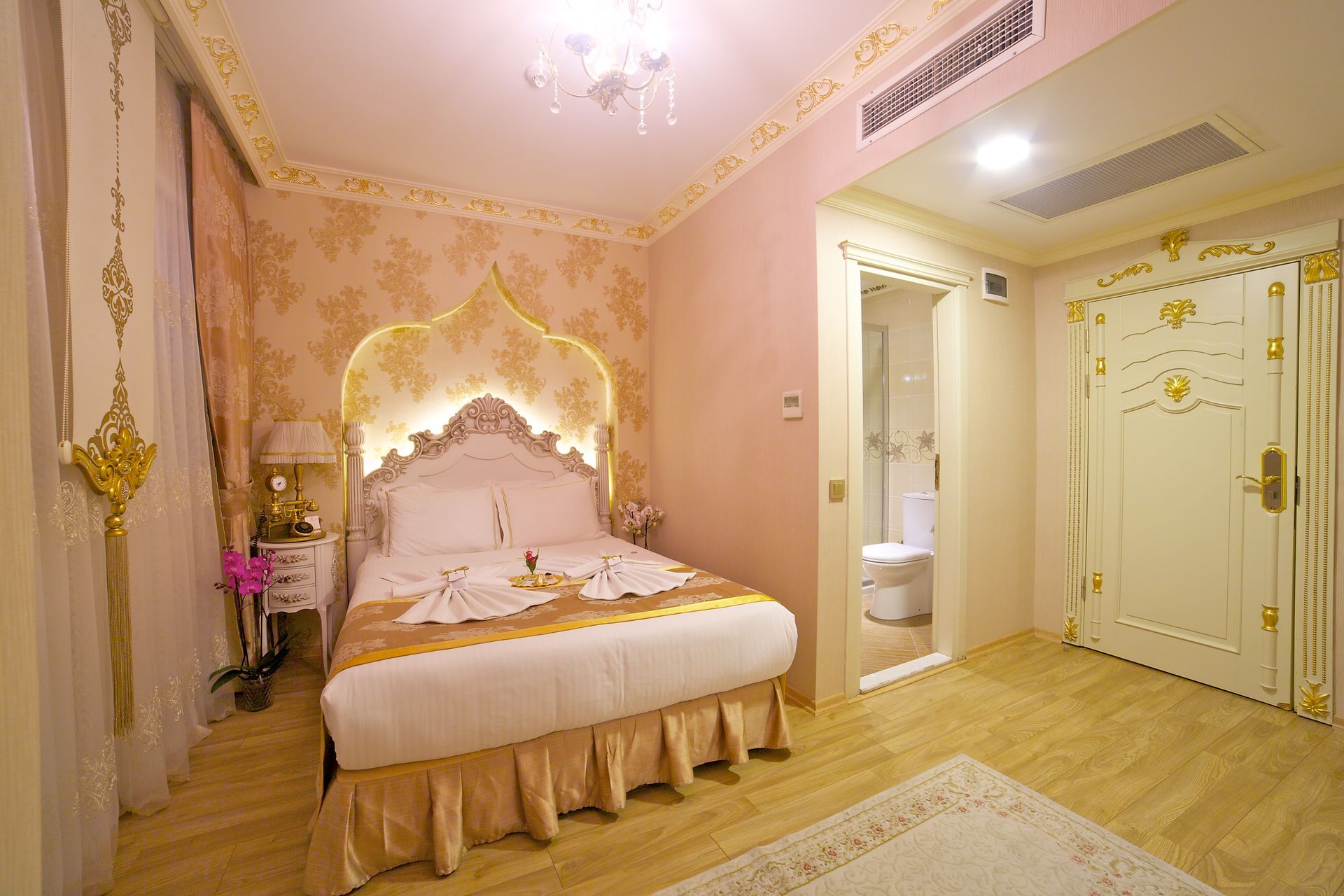 Istanbul white house hotel | Pink bedroom with ornate canopy bed, gold accents, and white double doors.