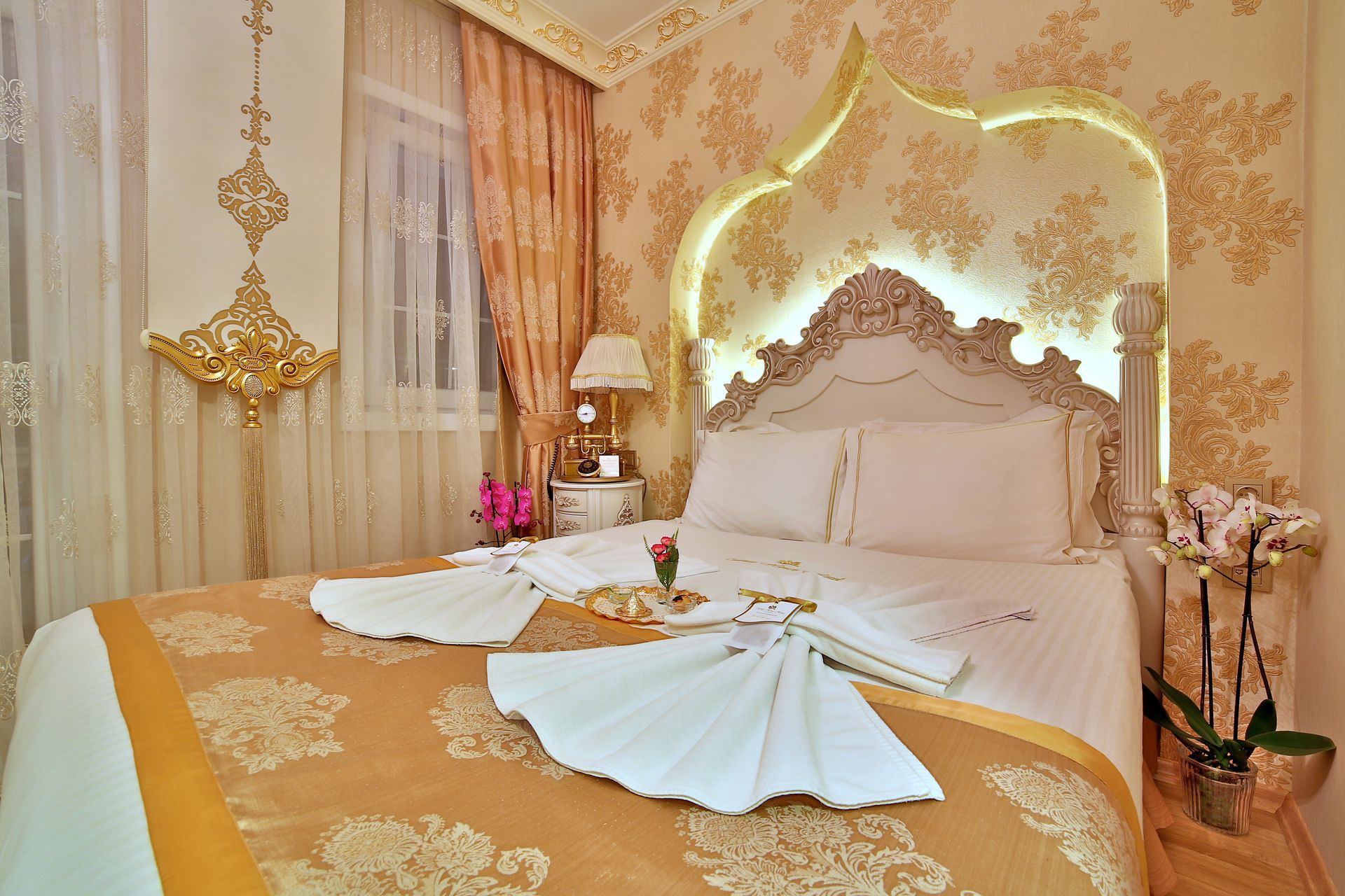 Istanbul white house hotel | Elegant gold-and-white bedroom with ornate decor, and folded towels arranged on the bed