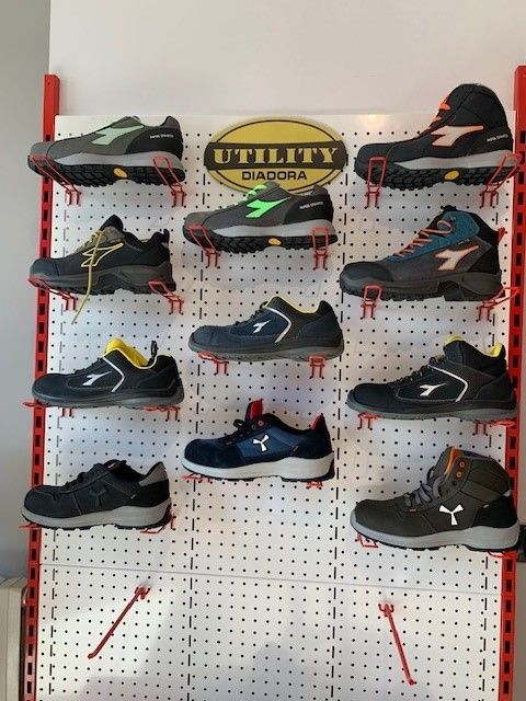 Esposizione di scarpe da lavoro Diadora Utility su un pannello forato con logo.
