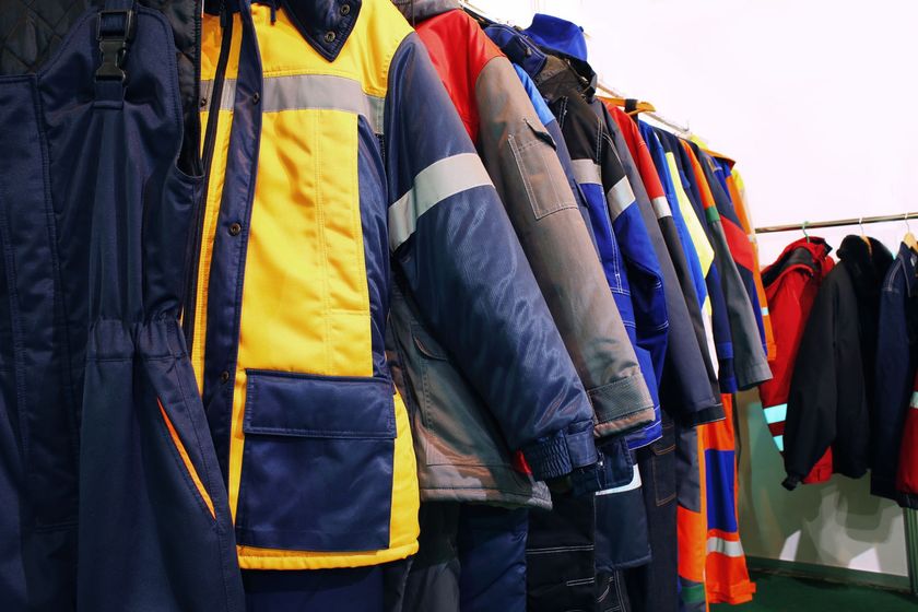 Giacche da lavoro appese a un attaccapanni; colori giallo, blu e arancione.