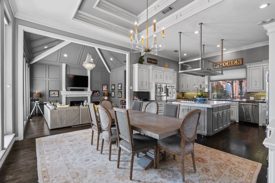 Bright modern kitchen and dining area with gray cabinetry, chandelier, and large island