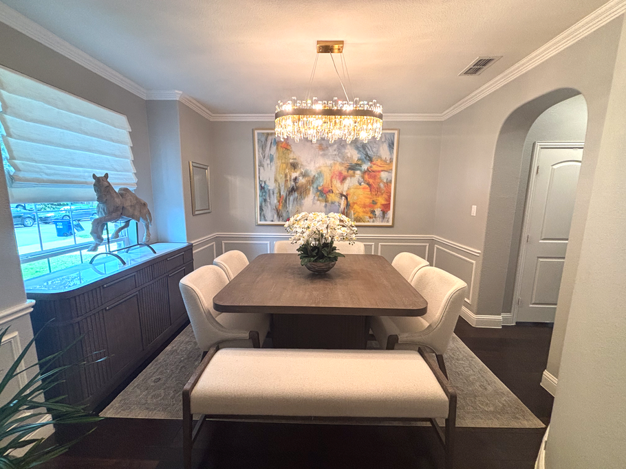 Elegant dining room with gray walls, chandelier, large abstract painting, and white upholstered chairs around a table