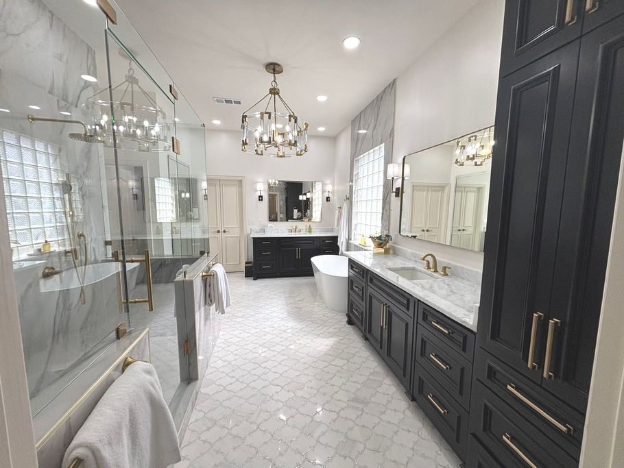 Bright modern bathroom with glass shower, dark vanity cabinets, large mirror, and patterned white floor tiles