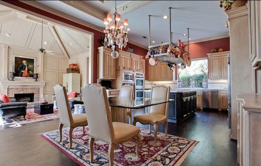 Elegant dining room with red chandelier, glass table, beige chairs, and fireplace in a bright home interior