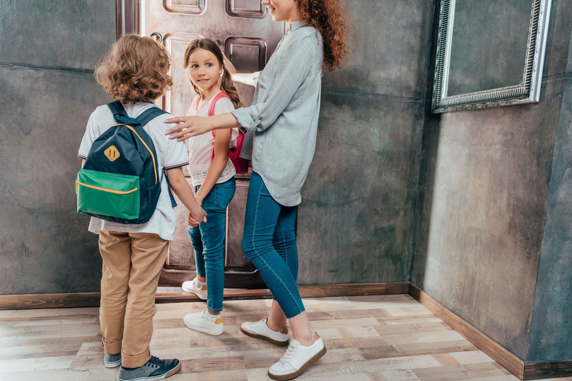A mother preparing her children for school transportation pickup. A mother preparing her children for school transportation pickup.