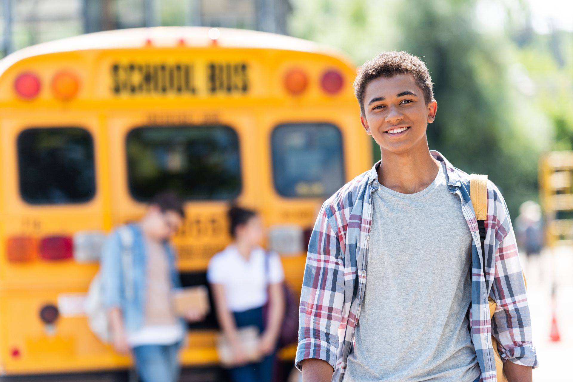 Schoolboy looking at camera in front of school bus. Schoolboy looking at camera in front of school bus.