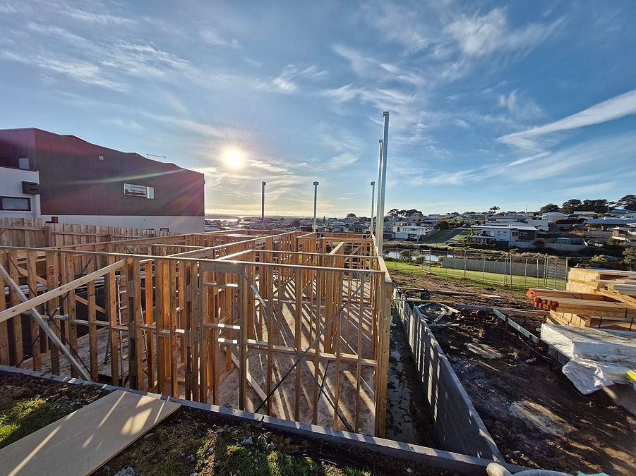 Construction site with wooden frame structure, sunny day, blue sky.