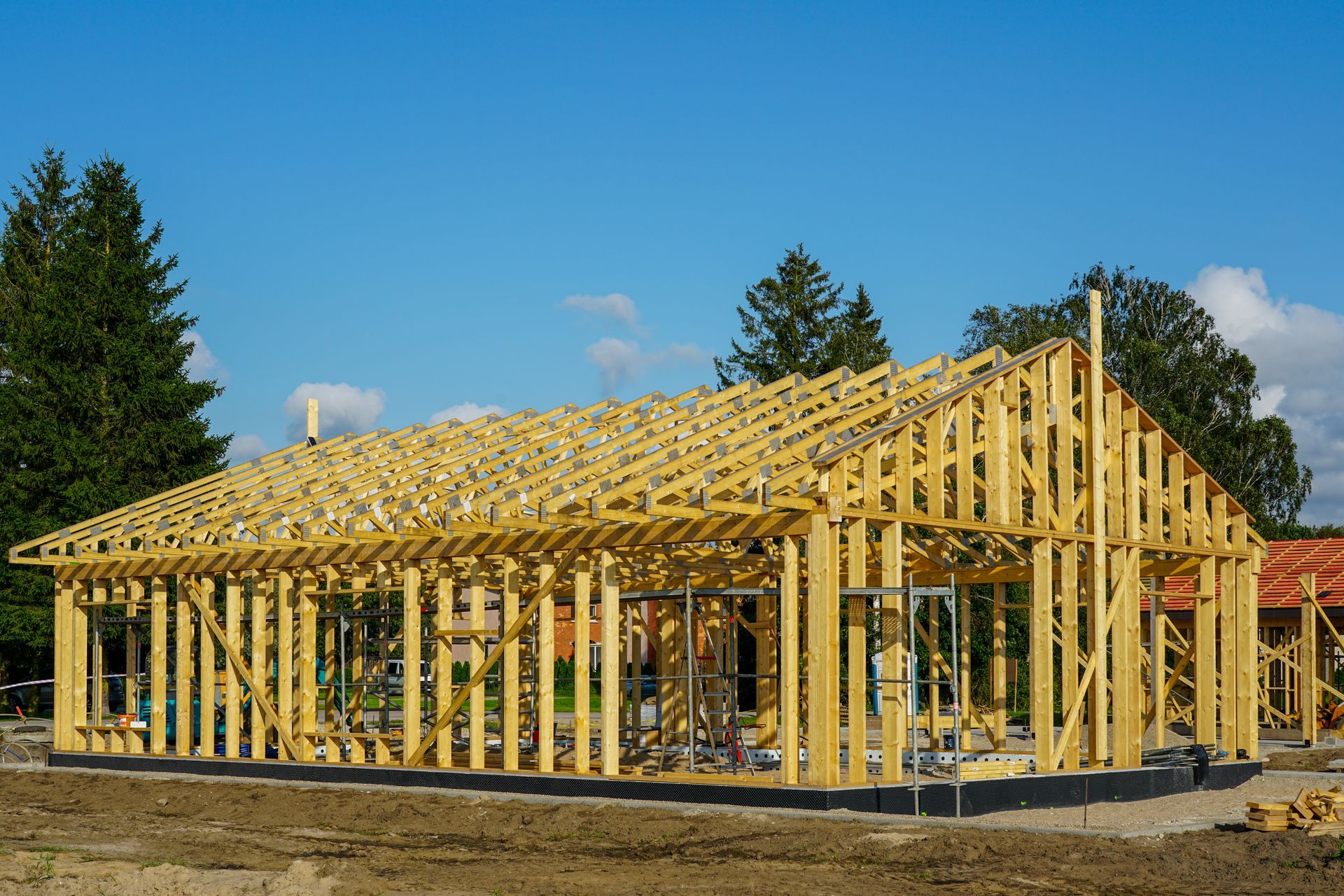 New modern wooden house frame construction with roof trusses under blue sky on building site.