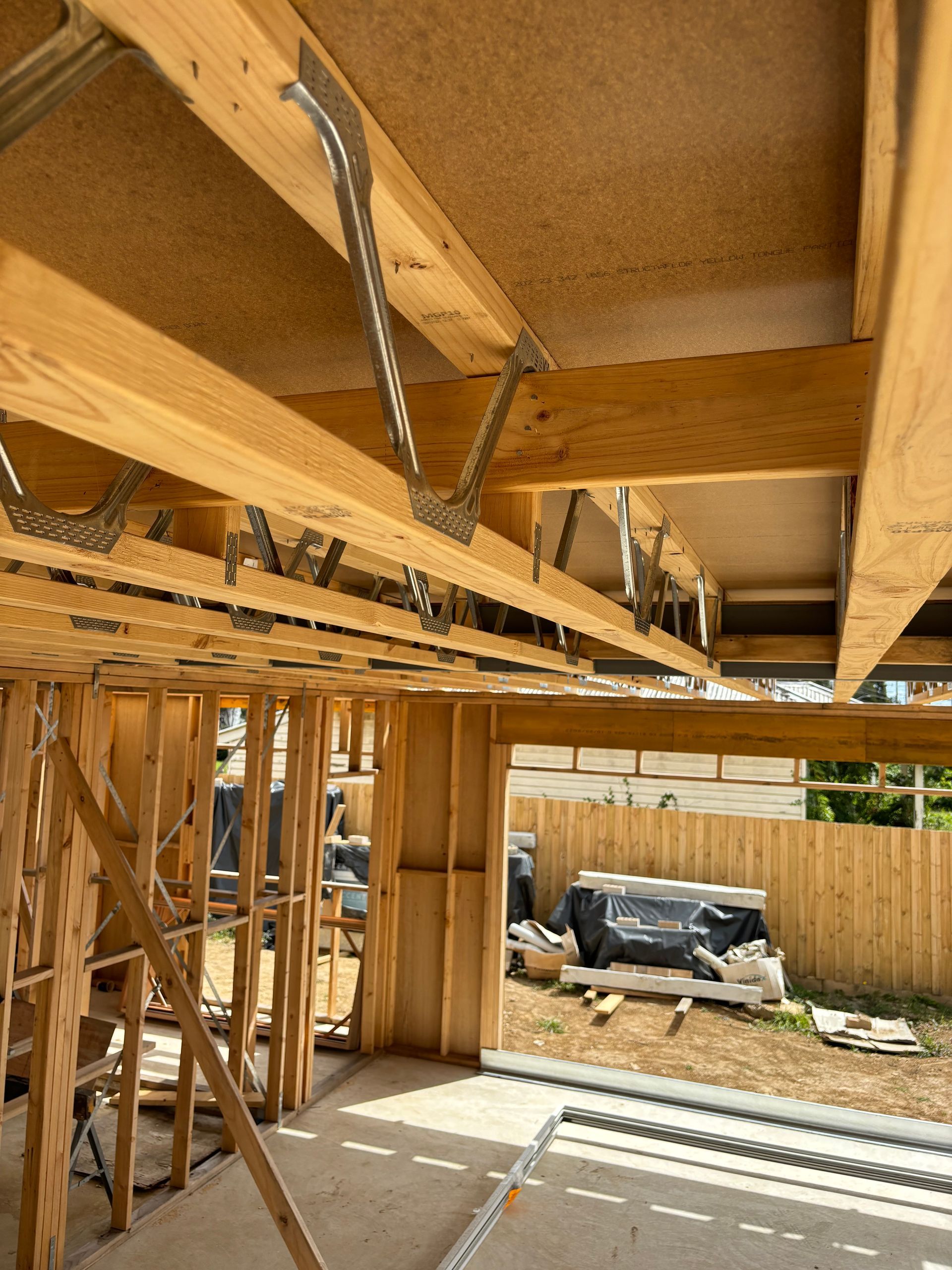 Wooden framework of a building under construction, with beams and metal connectors visible.