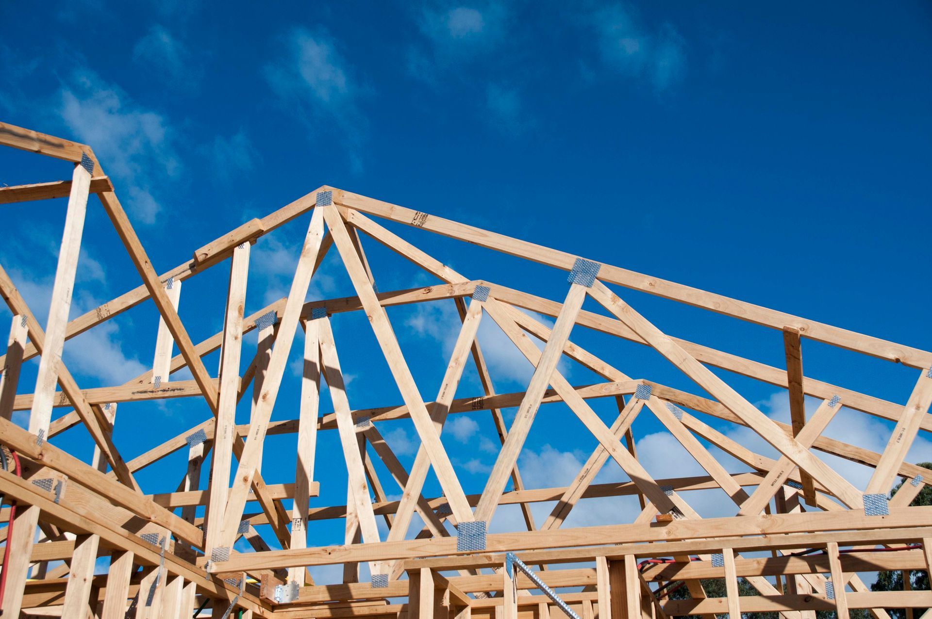 Wooden house frame against a bright blue sky.