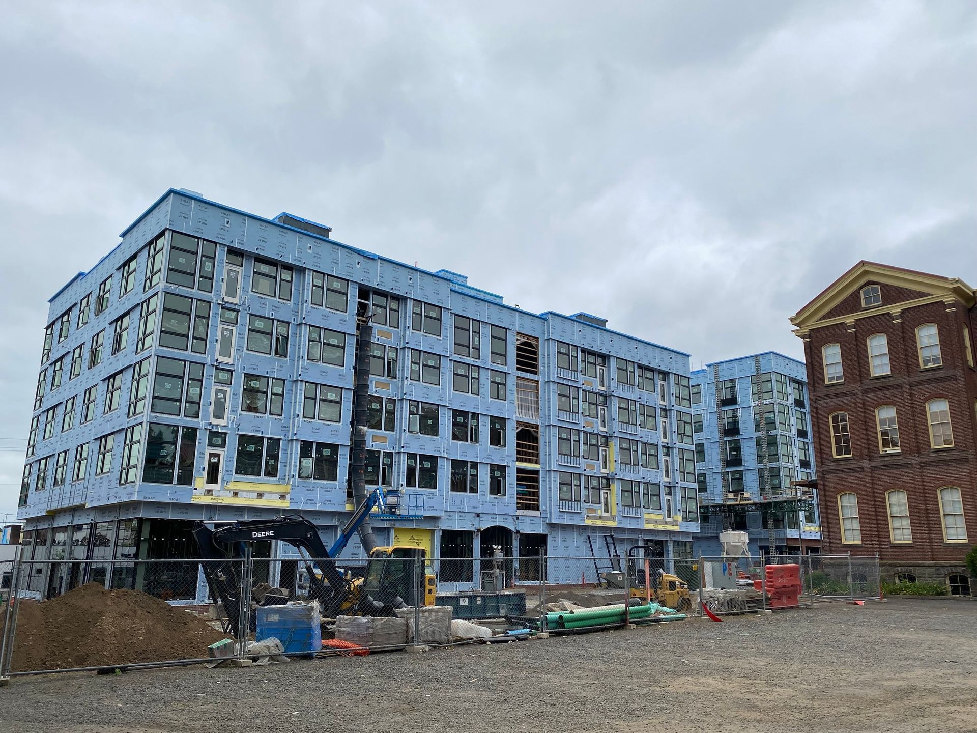 A large blue building is being built next to a brick building.