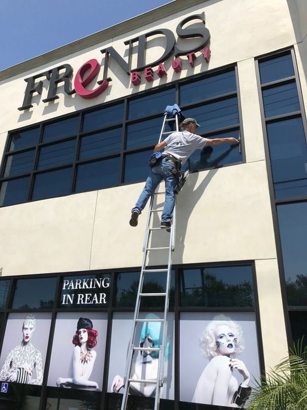 A man on a ladder is cleaning the windows of a building