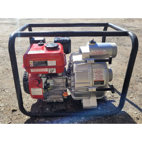 A water pump with a red engine is sitting on the ground.