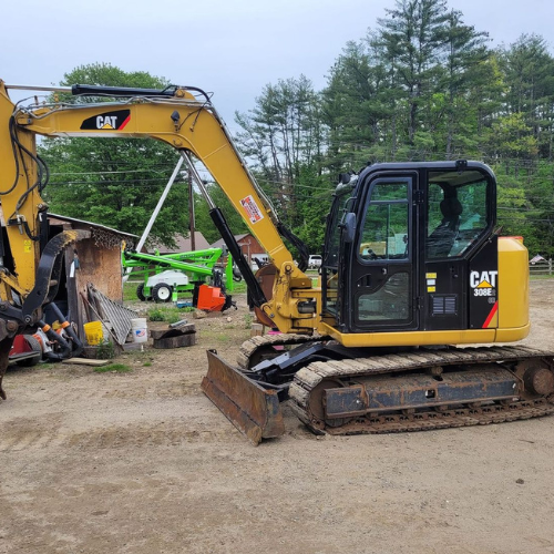 A yellow cat excavator is parked in a dirt lot.