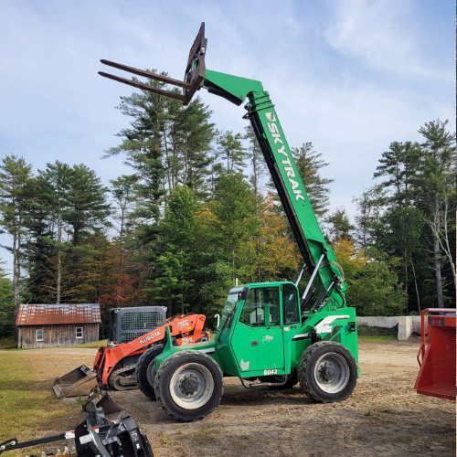 A green skytrail forklift is parked in a dirt lot