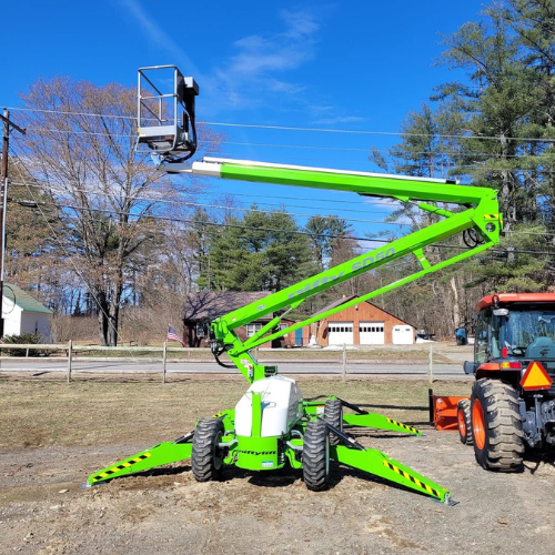 A green crane is parked next to a red tractor