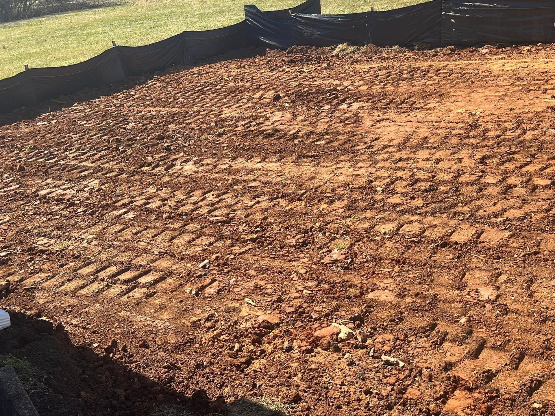 Brown dirt lot with tire tracks, possibly for construction.