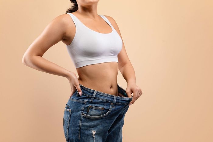 a woman is wearing a white bra and blue jeans