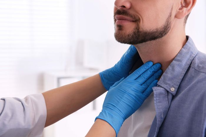 a doctor is examining a man 's thyroid gland