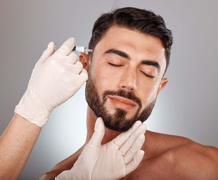 a man with a beard is getting a botox injection in his face