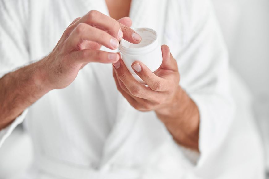 a man is holding a jar of cream in his hands