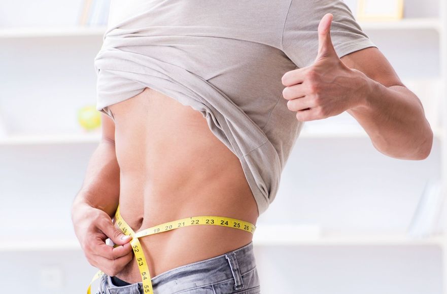 a man is measuring his waist with a tape measure and giving a thumbs up