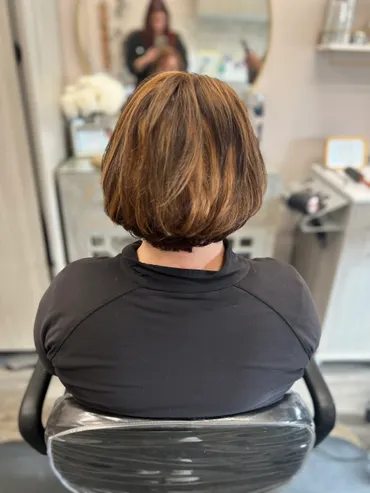 Person with brown and blonde highlighted bob haircut sits in a salon chair.