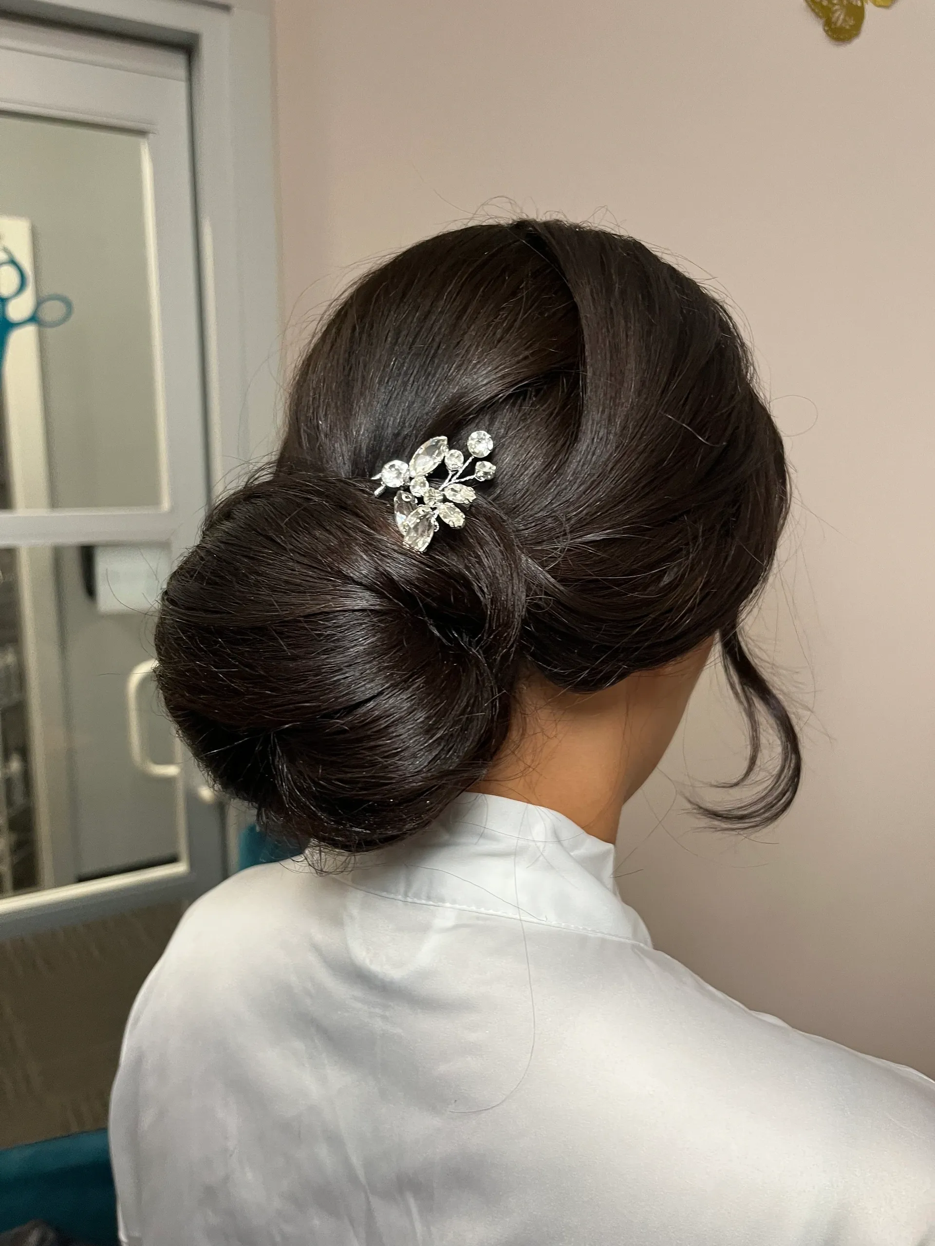 Woman with dark hair styled in a low bun, adorned with a jeweled hairpin.