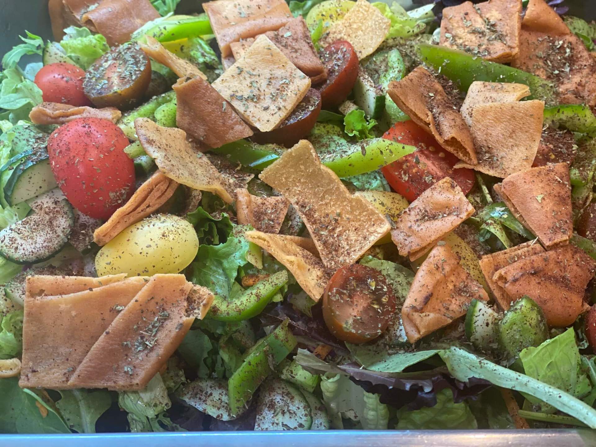 A close up of a salad with vegetables and pita chips