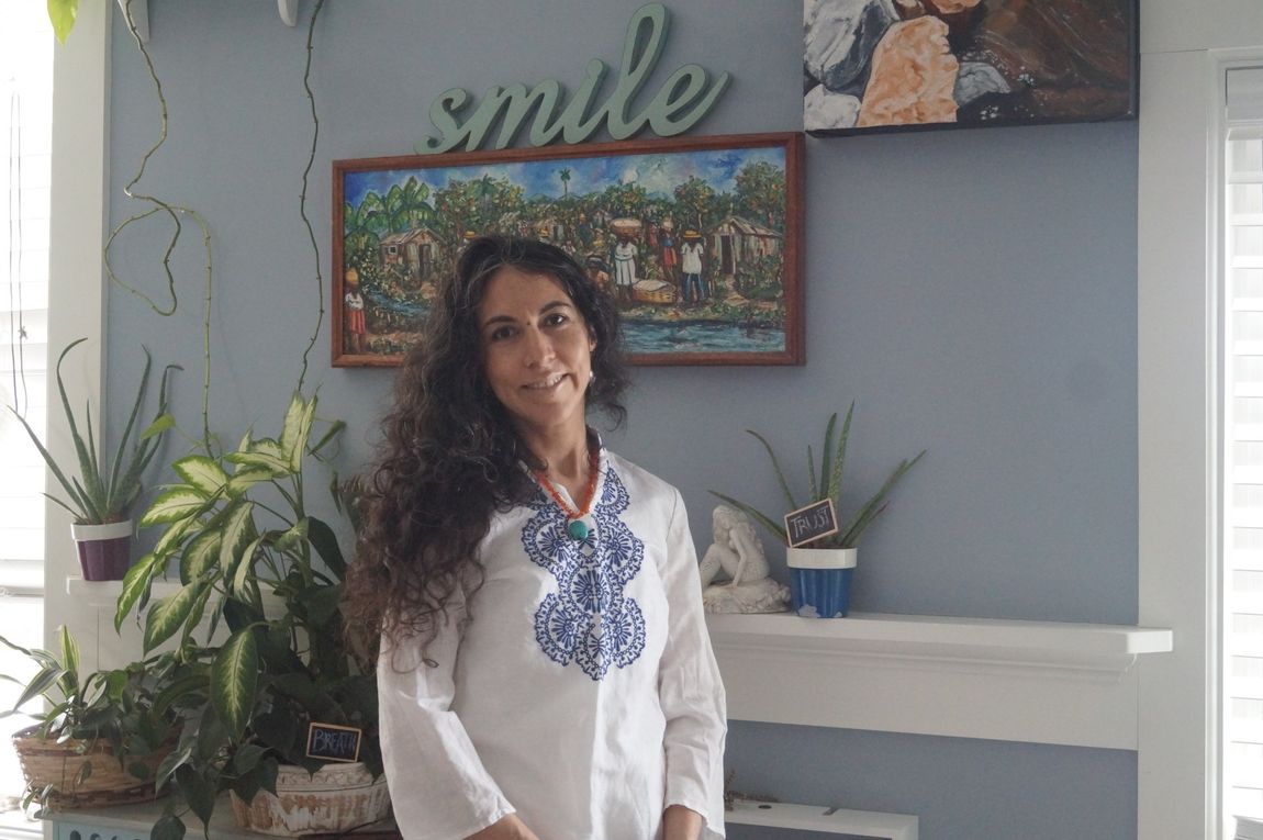 A woman is standing in front of a wall with a sign that says smile.