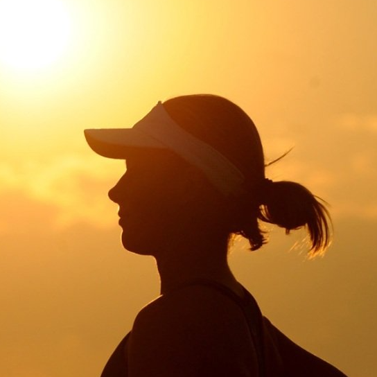 A silhouette of a woman wearing a hat and visor
