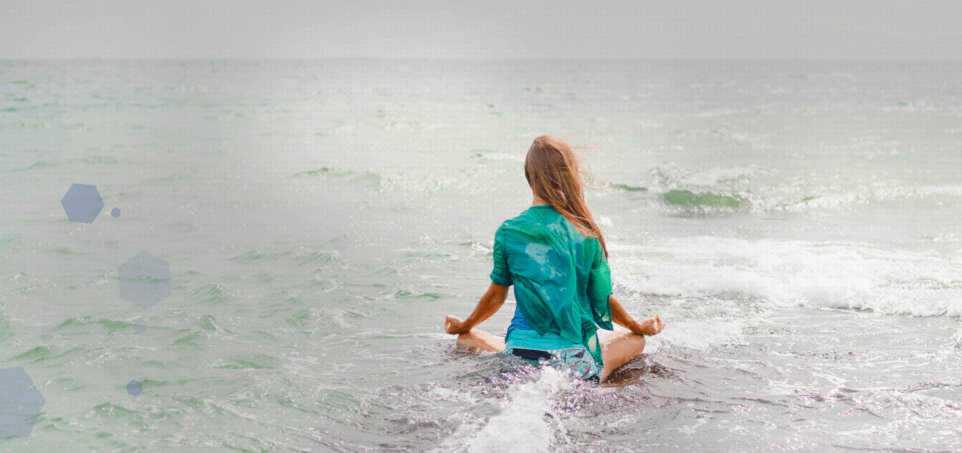 A woman is sitting in a lotus position in the ocean.