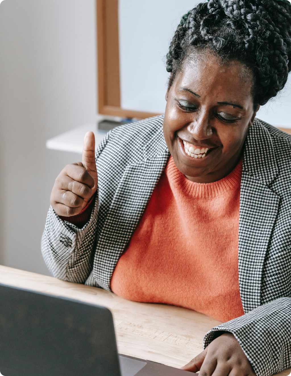 A woman is giving a thumbs up while using a laptop computer.