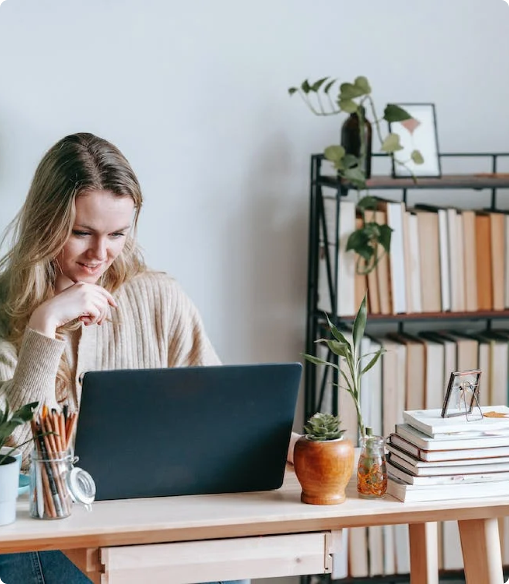 A woman is sitting at a desk using a laptop computer.