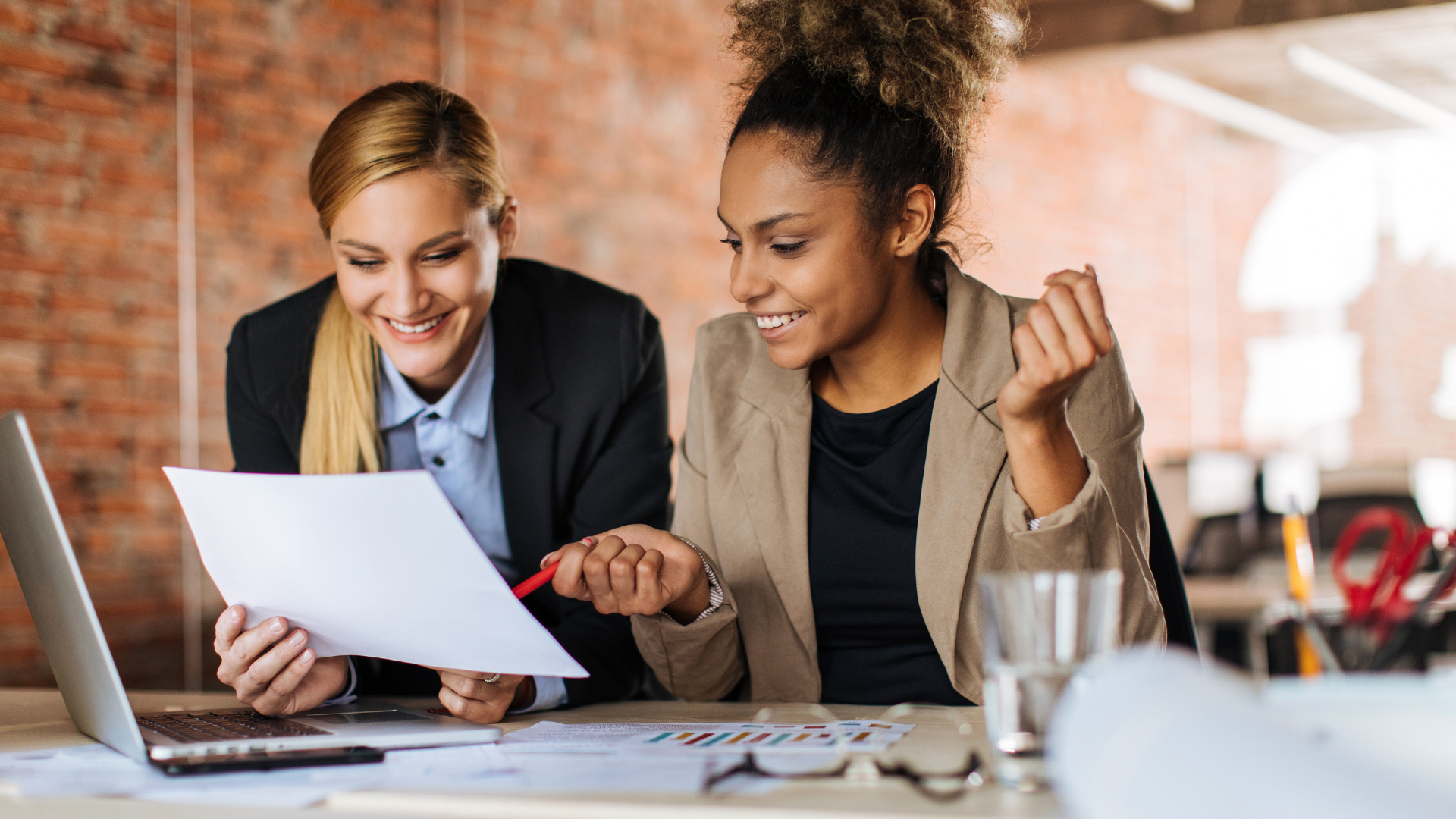 Two women are sitting at a table looking at a piece of paper.