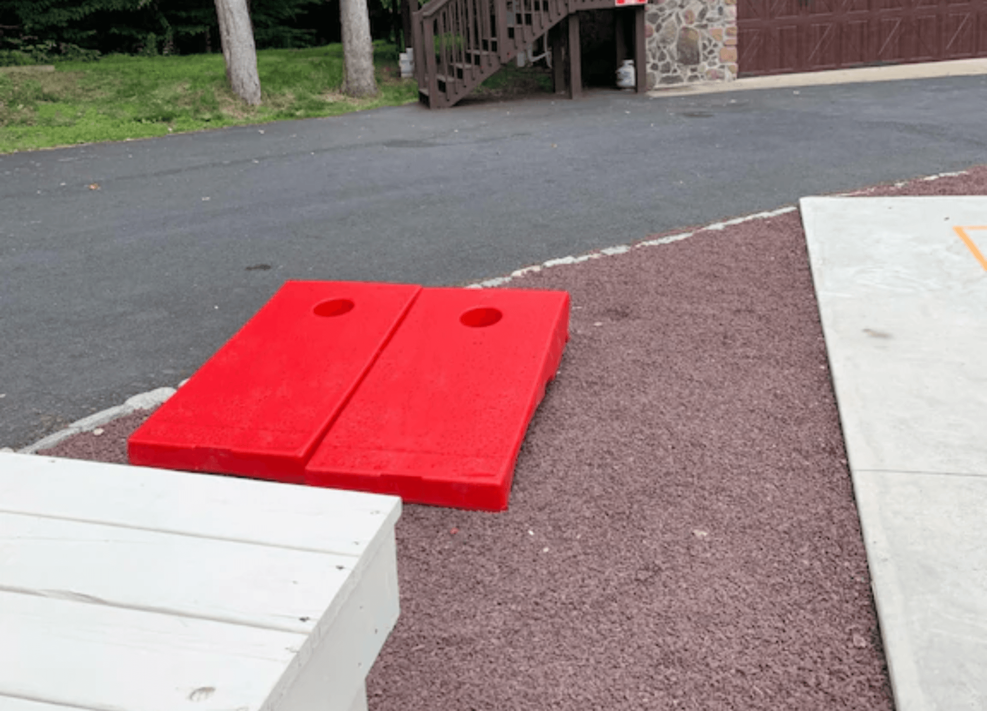 Two red cornhole bags are sitting on the side of the road.