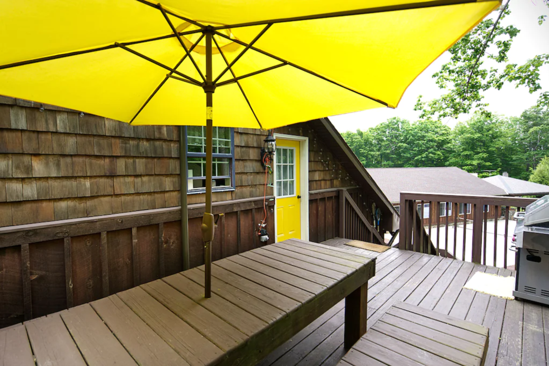 A yellow umbrella is sitting on a wooden deck