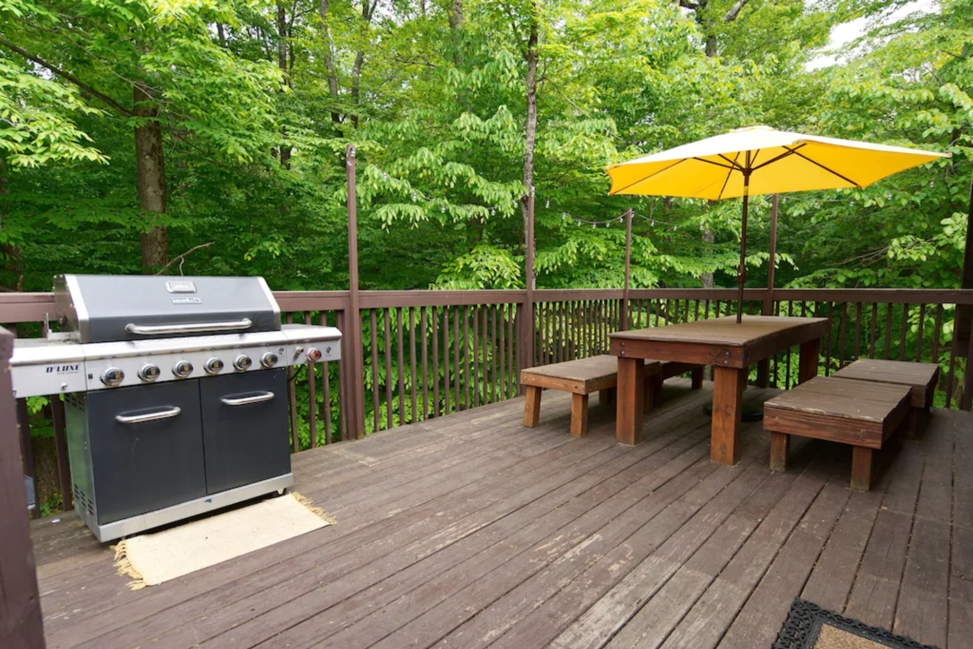 A wooden deck with a grill and umbrella on it