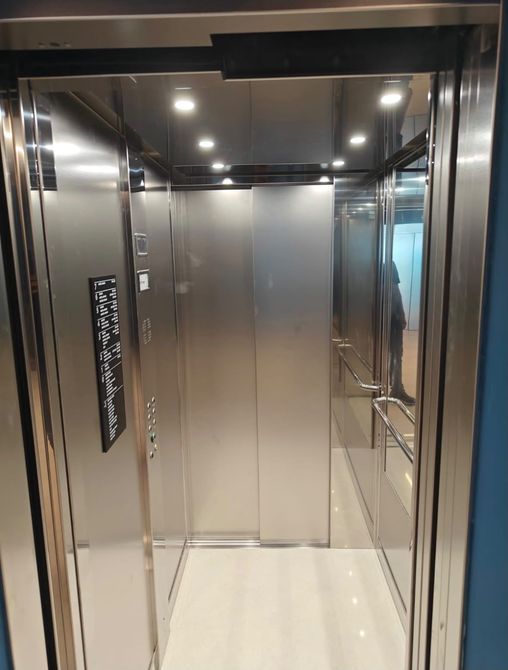 Interno vuoto di un ascensore moderno, con pareti in acciaio inox e luci intense sul soffitto