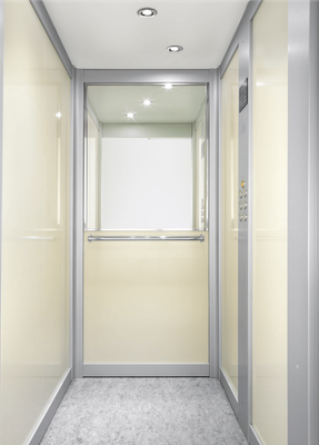 Interno vuoto di un ascensore moderno, con pareti beige, pavimento grigio e faretti incassati nel soffitto
