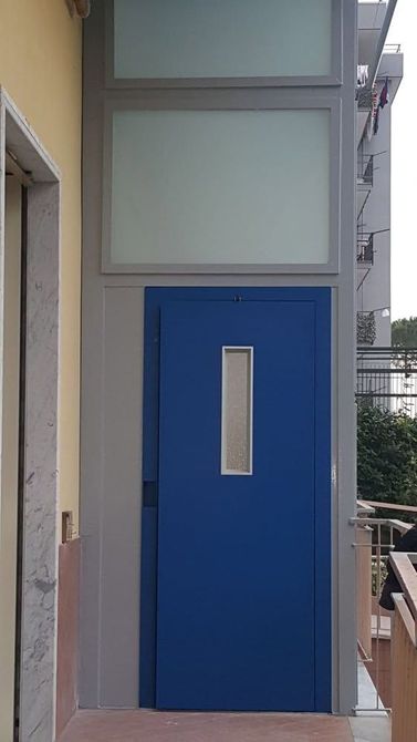 Porta blu con una finestra stretta nel corridoio di un edificio o in una zona del balcone