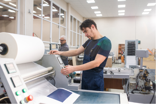 Worker operating a large printing machine in a bright print shop