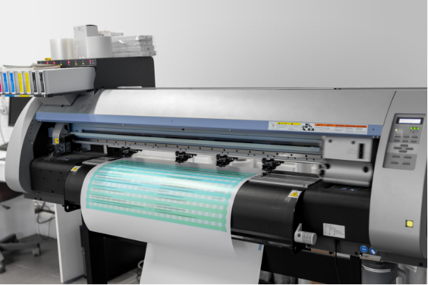 Large-format printer printing a turquoise banner in a print shop